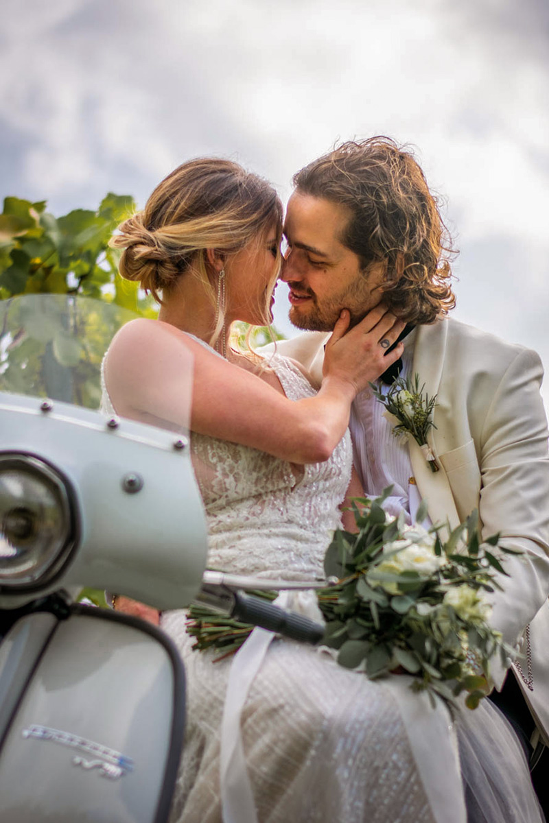 wedding portrait of a couple about to kiss while sitting on a vintage motorcycle