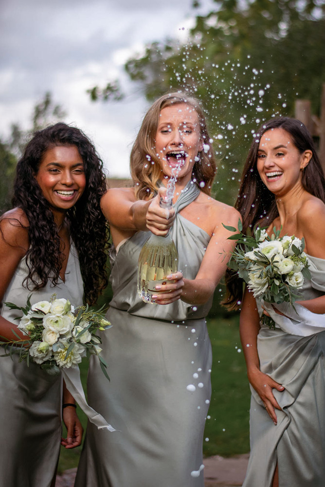 bridesmaids celebrating and opening a bottle of champagne